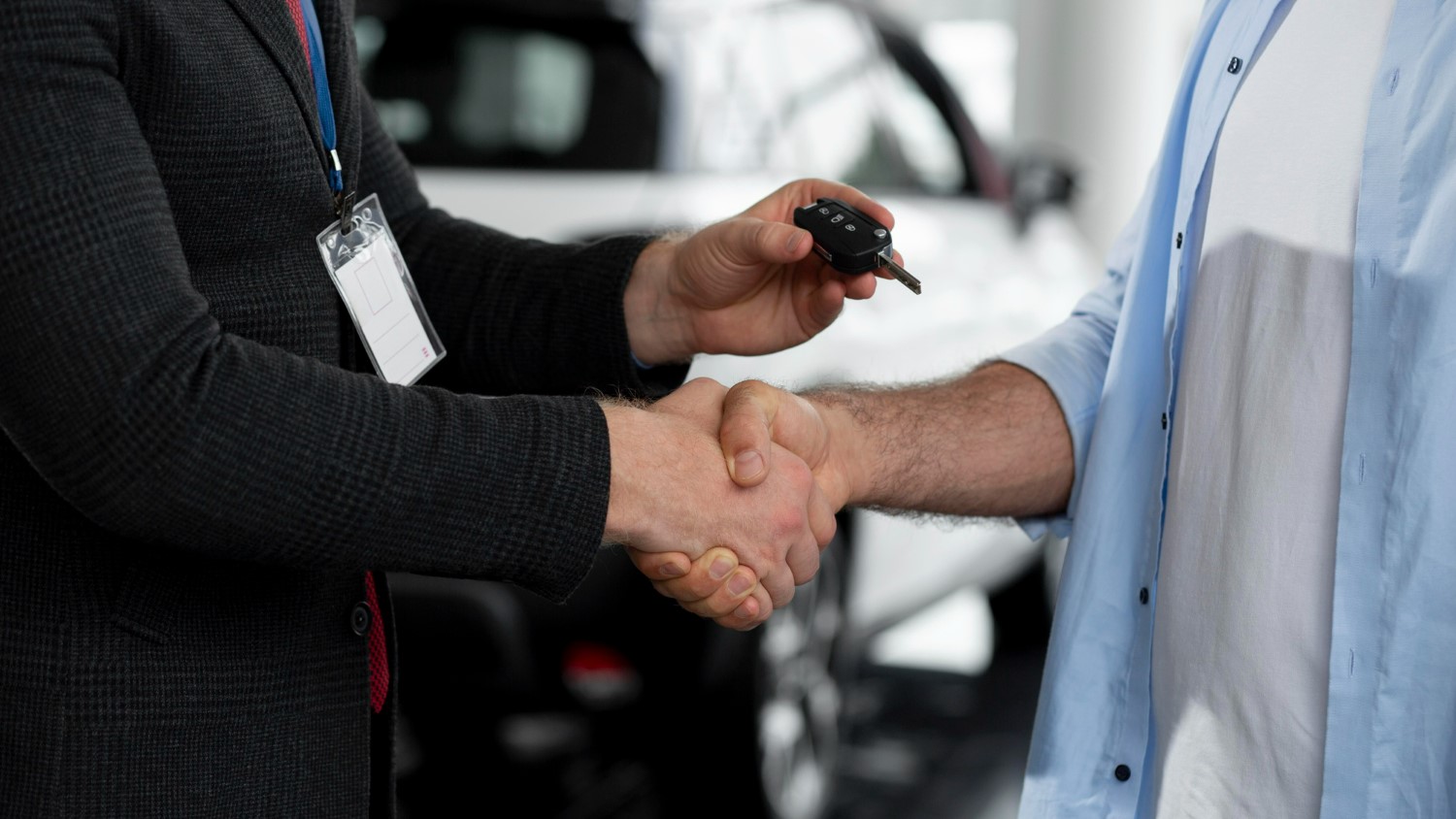 image of car key handover with car in background